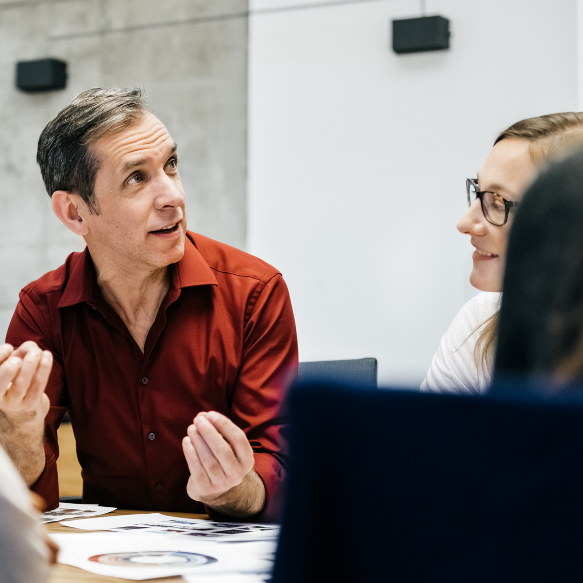 Leaders and Innovators Businessman in red shirt speaking to a group of business people in a boardroom.